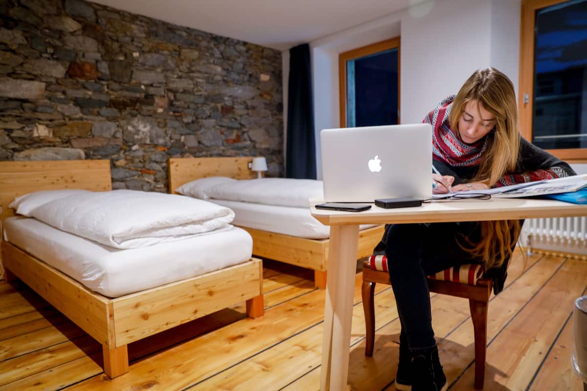 Une pièce avec deux lits en bois, un mur en pierre et un plancher en bois.