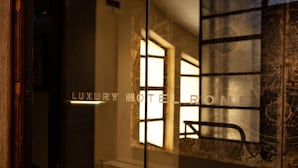 L’entrée d’un hôtel de luxe, avec une porte en verre qui reflète la lumière intérieure et une fenêtre offrant une vue.