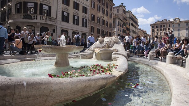 Une fontaine publique dont l’eau jaillit de plusieurs bassins, entourée d’une foule de personnes.