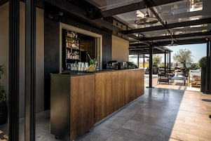 Un'area bar moderna con un bancone in legno, diverse bottiglie e una macchina da caffè.
