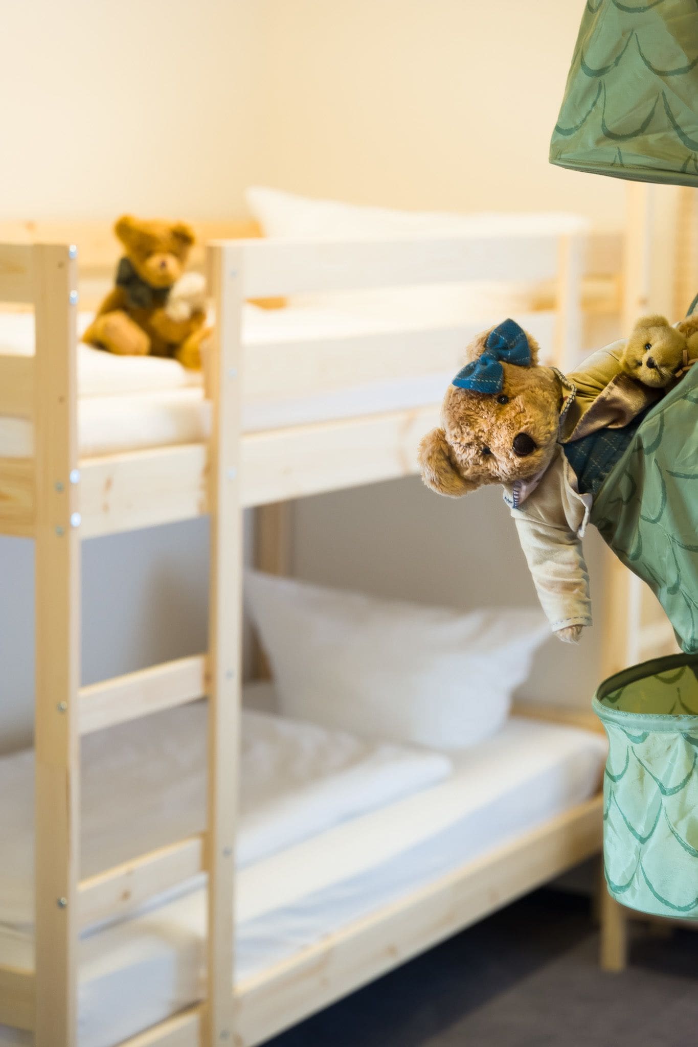 Una cama litera con dos niveles, cada uno con colchón y almohadas. Un osito de peluche está apoyado en la litera inferior.