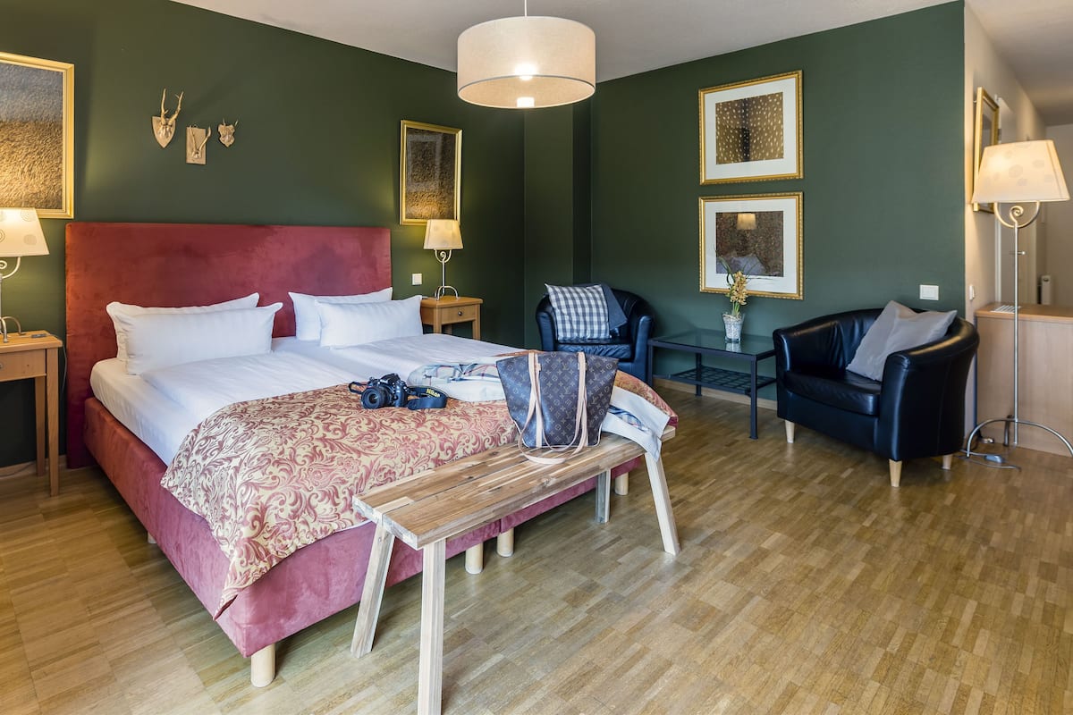 A hotel room with a large bed, a desk, a chair, and a lamp.