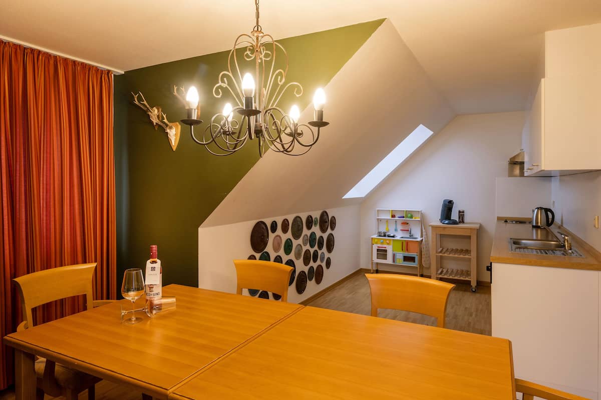 A dining area with a wooden table, chairs, a chandelier, and a wall with decorative plates.