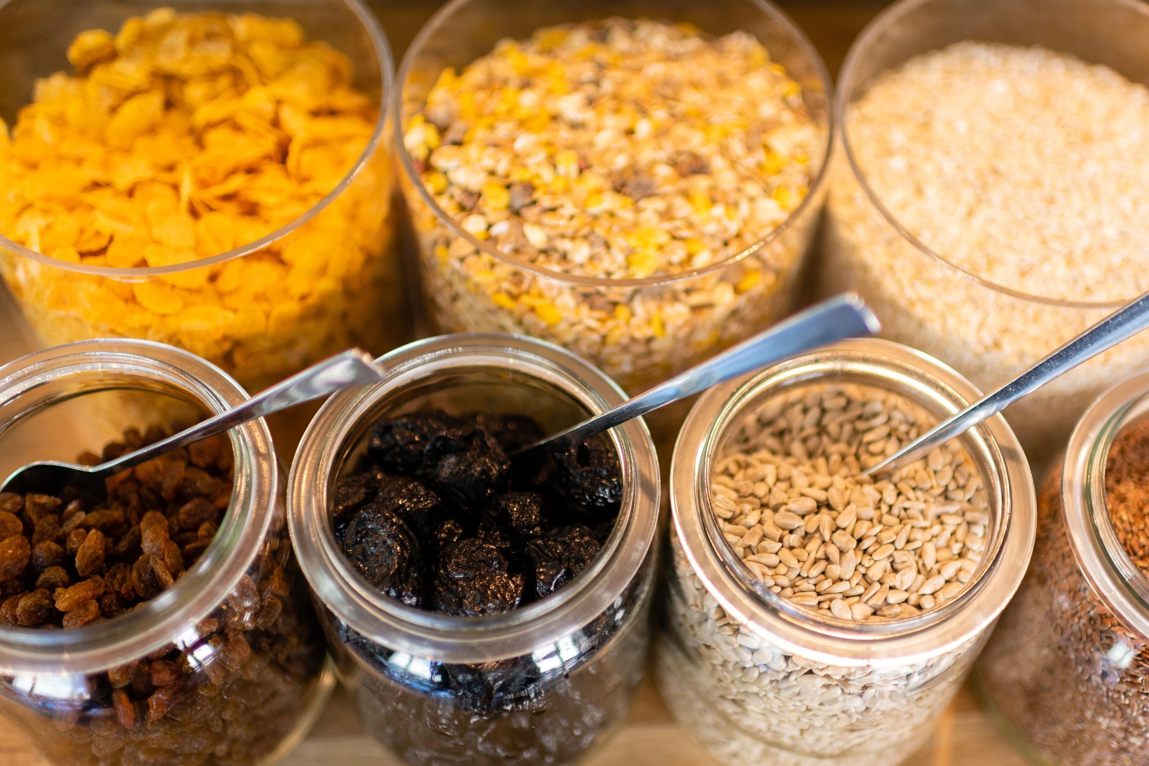On trouve une variété d’aliments en conserve dans des bocaux en verre, notamment des céréales et des fruits secs.