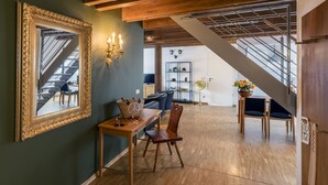 A spacious living area with a staircase, a dining table with chairs, a large mirror, and a bookshelf. - Apparthotel Steiger Bad Schandau (Bad Schandau)