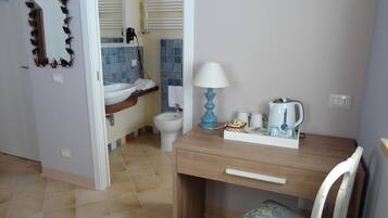 Ein Badezimmer mit Waschbecken, Toilette und Bidet. Ein Spiegel, ein Handtuchhalter und eine Lampe befinden sich auf der Ablagefläche.