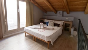 Un dormitorio con techo de madera, una cama con ropa de cama blanca, una decoración con forma de corazón y una ventana con cortinas.