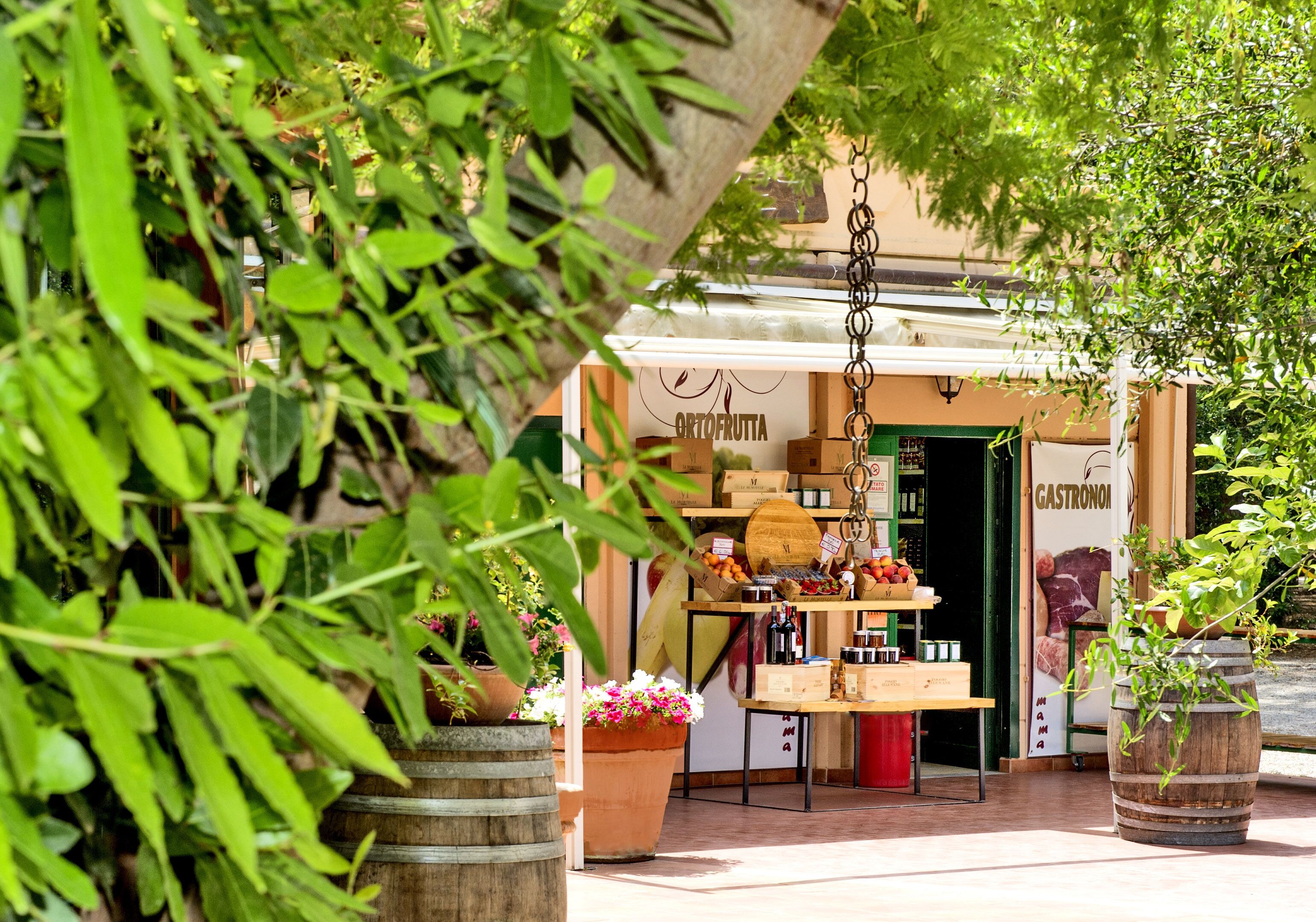 Un mercado al aire libre con barriles de madera, una mesa con frutas y un letrero que dice "ARTIFRUTA".