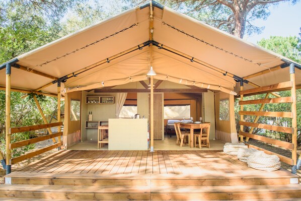 Una terraza de madera con zona cubierta, una mesa y un banco.