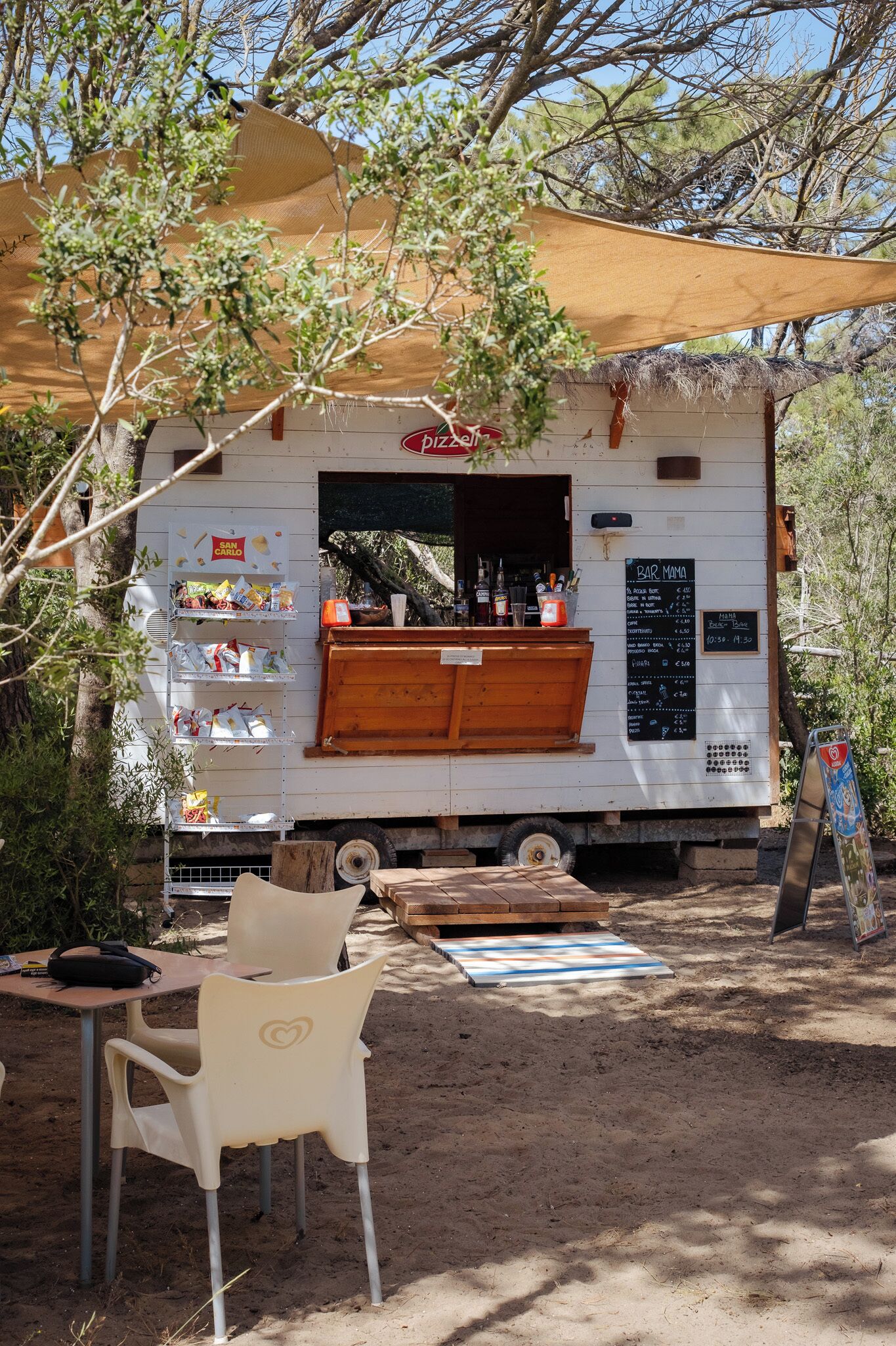 Un bar mobile doté d’un tableau affichant le menu, de places assises en plein air et d’un espace ombragé.