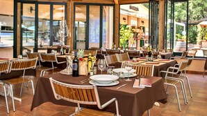 A restaurant with multiple tables set for dining, featuring wooden chairs and a brown tablecloth. - Camping Maremma Sans Souci (Castiglione della Pescaia)