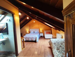 A bedroom with a sloped ceiling, a bed, bedside tables, and a window.