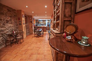 A cozy kitchen with a stone wall, wooden cabinets, and a dining area with chairs and a table.