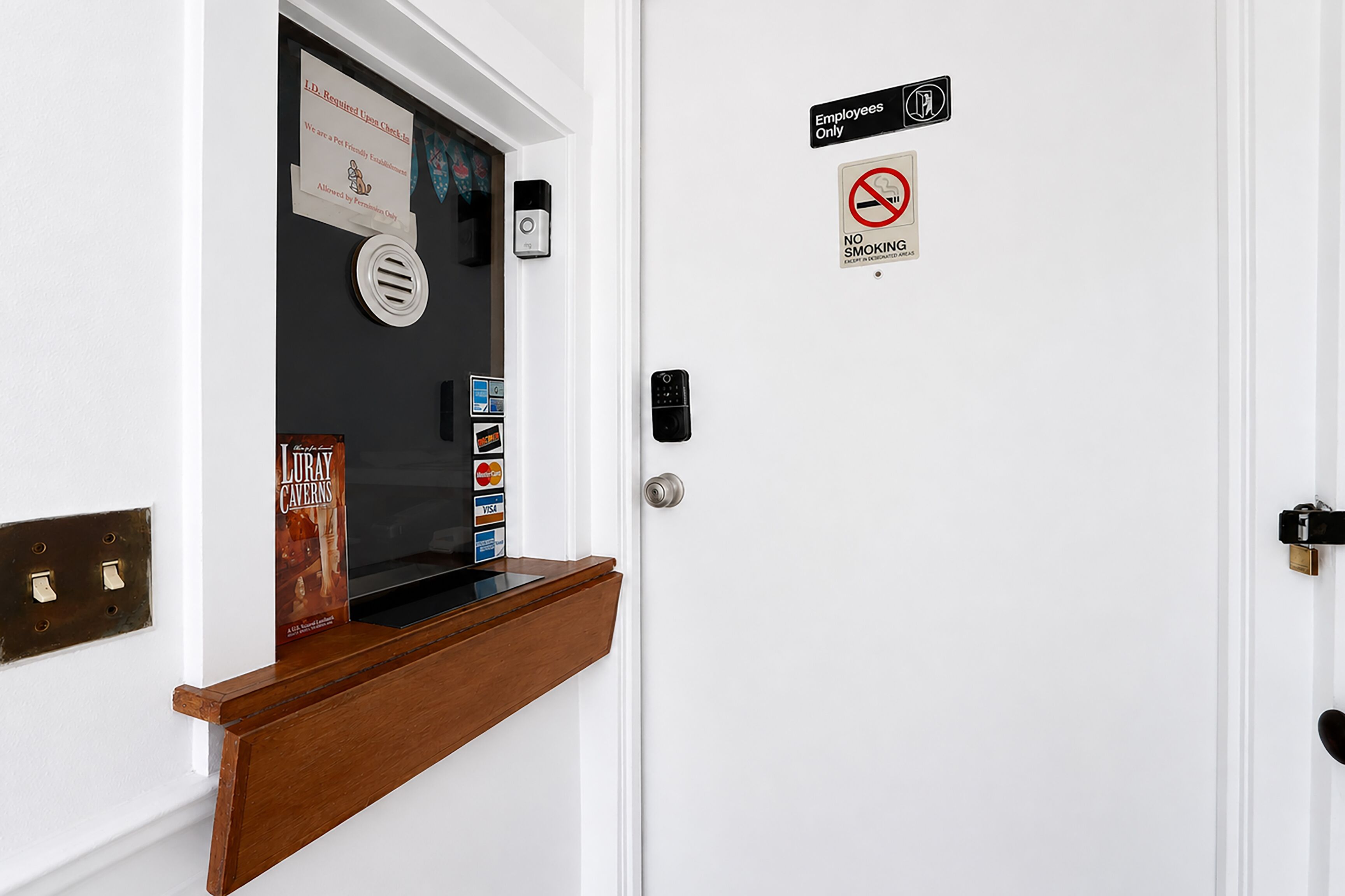 A hotel room door with a pet-friendly sign, a no smoking sign, and a keycard reader.