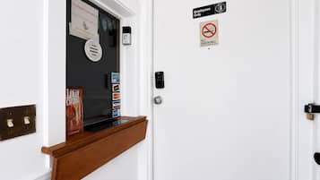 A hotel room door with a pet-friendly sign, a no smoking sign, and a keycard reader.