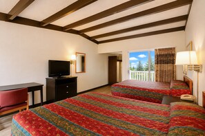 A hotel room with a bed, a desk, a television, and a balcony with a view of trees. - Hometown Inn Staunton VA near Hwy 11 (Staunton)