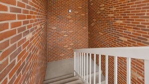 A staircase with a white railing, surrounded by brick walls. - Hometown Inn Staunton VA near Hwy 11 (Staunton)