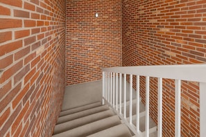A staircase with a white railing, surrounded by brick walls. - Hometown Inn Staunton VA near Hwy 11 (Staunton)
