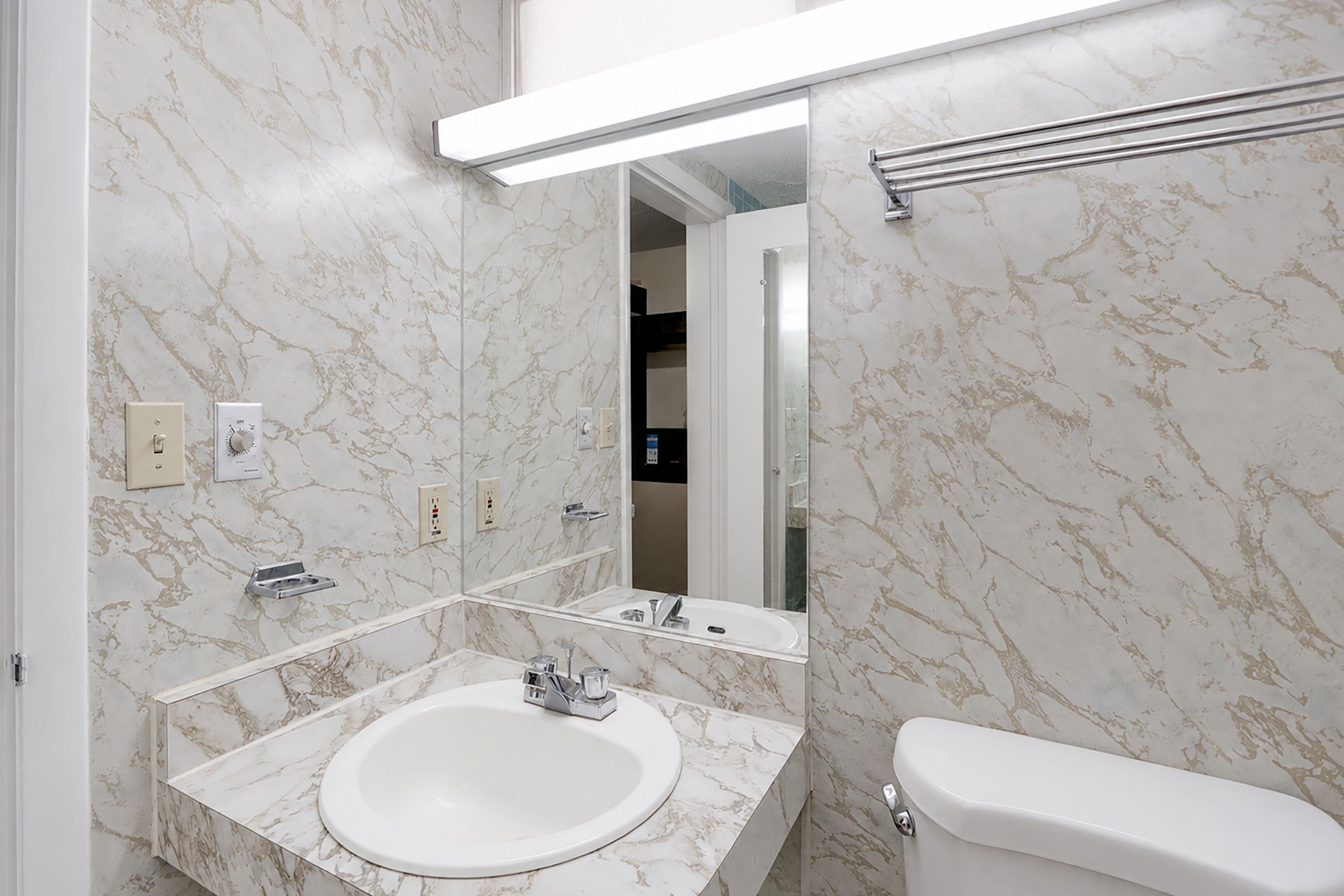A bathroom with a marble sink, a toilet, and a mirror.