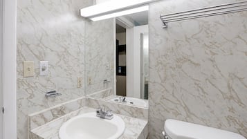 A bathroom with a marble sink, a toilet, and a mirror.