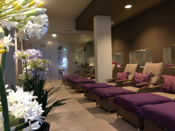 A spa room with wicker chairs, purple towels, and white flowers. - Hotel Steiger Sebnitzer Hof- Adults Only (Sebnitz)