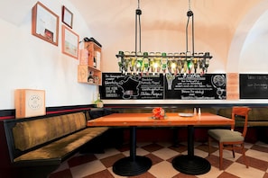 A bar area with a checkered floor, a wooden bench, a table with a flower centerpiece, and a wine rack with illuminated bottles. - Hotel Steiger Sebnitzer Hof- Adults Only (Sebnitz)