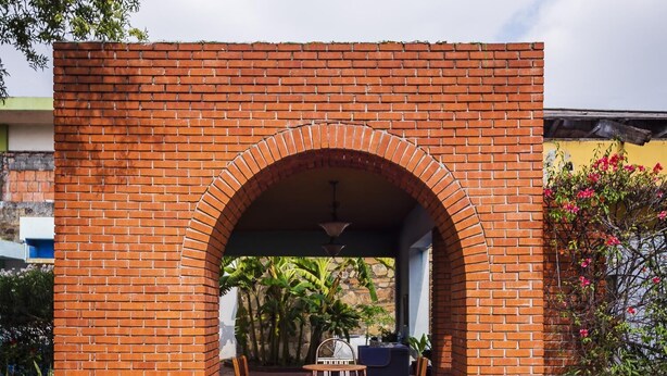 A brick archway leading to an outdoor patio area with a table and chairs.