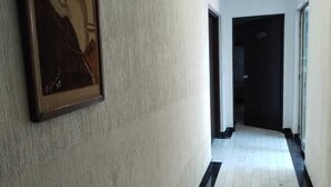 A hallway with a framed artwork on the wall, a tiled floor, and doors leading to other rooms.