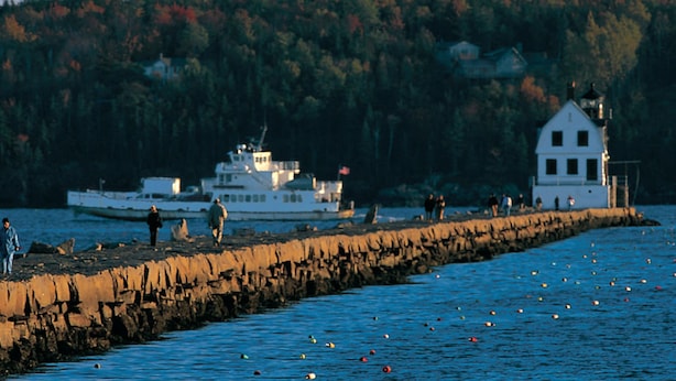 A pier extending into calm water with a boat docked at the end. - Berry Manor Inn (Rockland)