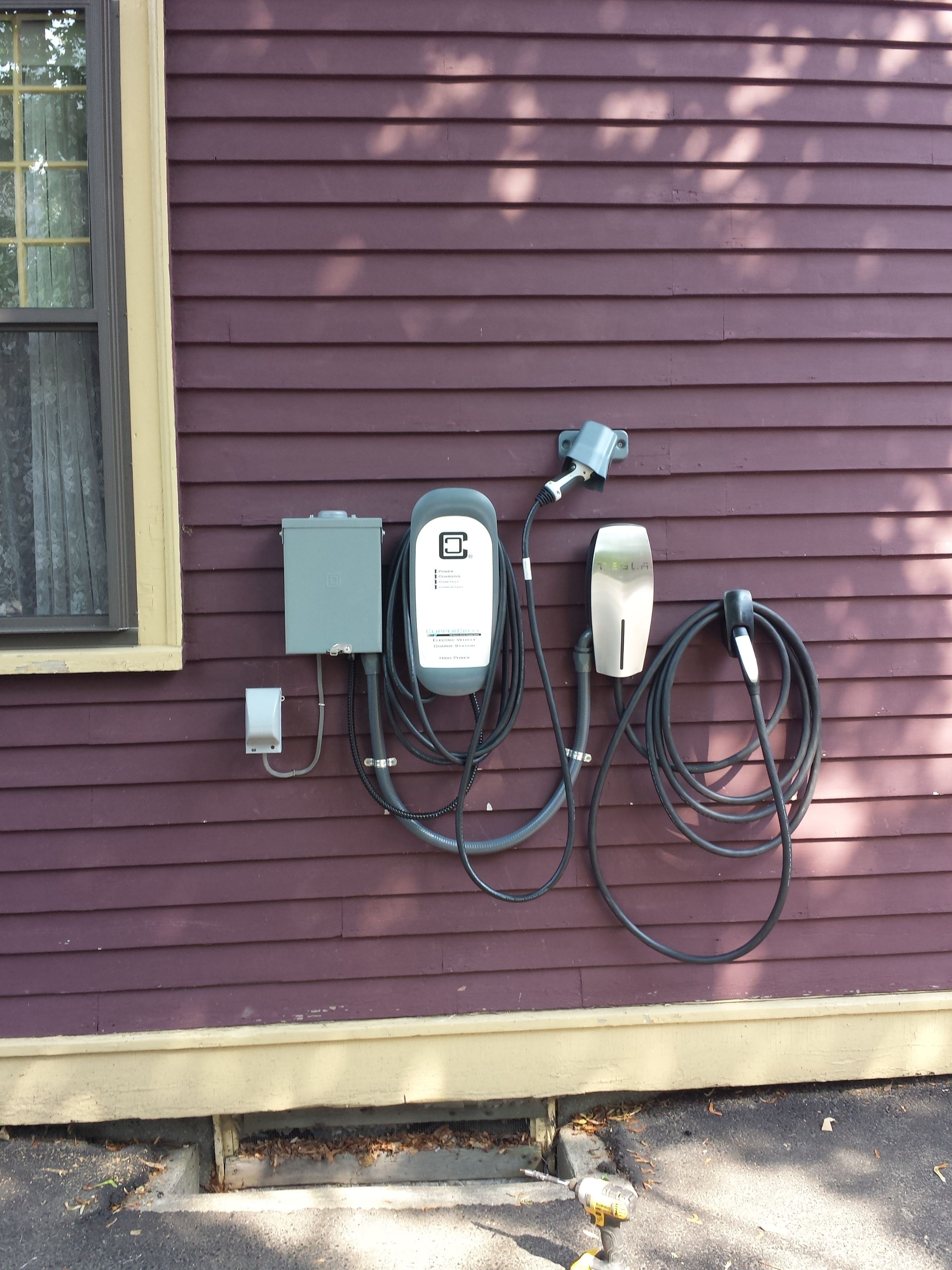 Instalación eléctrica exterior con un generador, toma de corriente y cables de extensión sujetos a una pared morada.