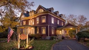 A large, two-story Victorian-style house with a wrap-around porch and a well-lit entrance. - Berry Manor Inn (Rockland)