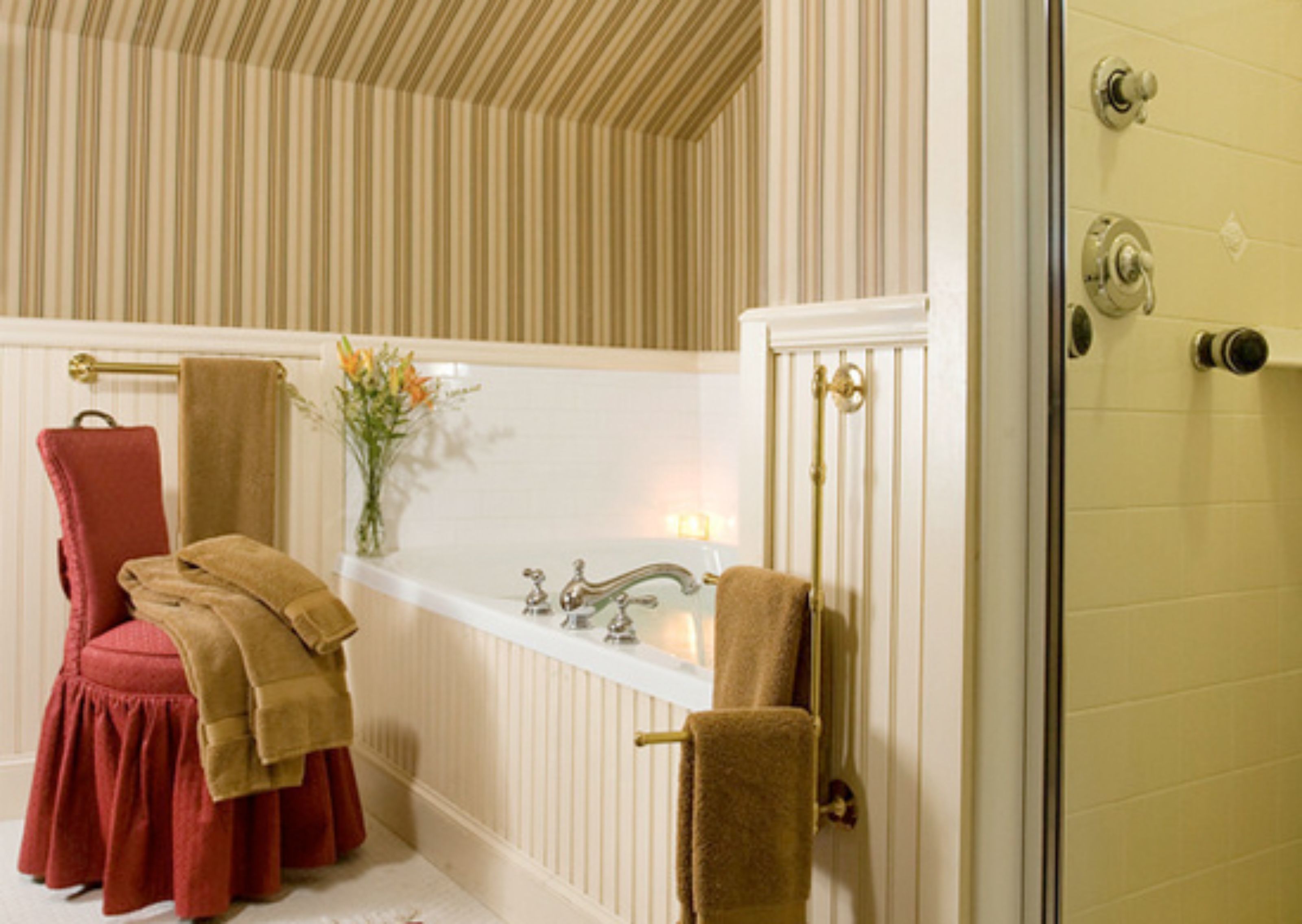 A bathroom with a bathtub, a red chair, and towels.