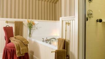 A bathroom with a bathtub, a red chair, and towels.