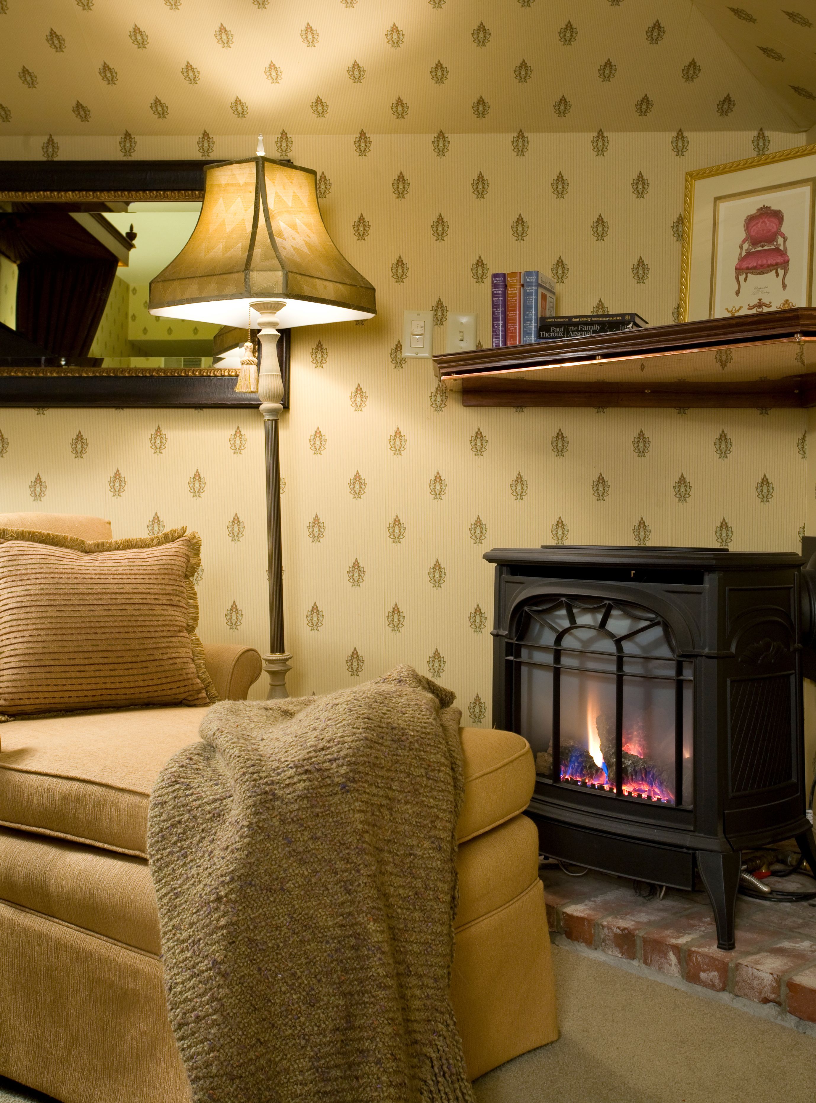 A cozy living room with a sofa, a lamp, a fireplace, and a bookshelf.