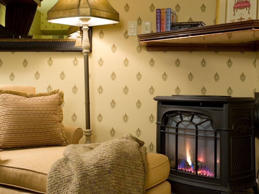 A cozy living room with a sofa, a lamp, a fireplace, and a bookshelf.