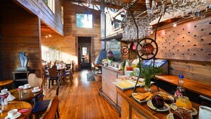 Um interior rústico em madeira com mesas de jantar, cadeiras e um balcão de buffet repleto de comida e bebidas.