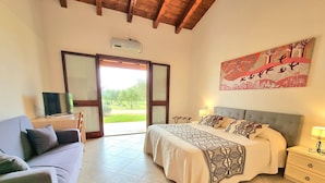 Un dormitorio con cama, sofá, televisión y un cuadro.
