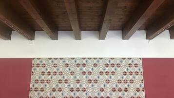 A room with a patterned floor, wooden ceiling beams, and a red wall.