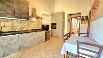 A modern kitchen with a built-in stove, oven, and a flat-screen TV. There is a dining area with a table and chairs.