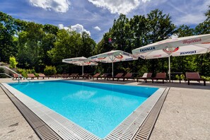 Una piscina al aire libre, sombrillas, tumbonas