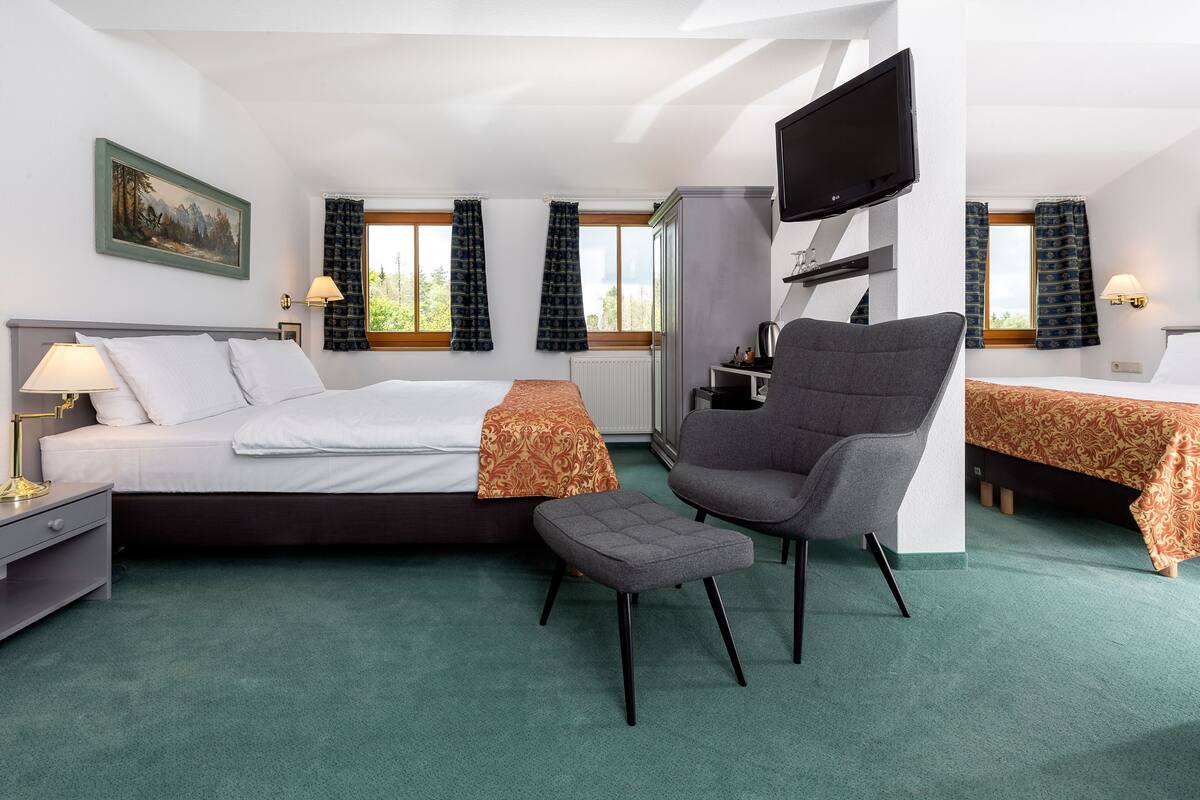 A hotel room with a large bed, a desk, a chair, and a television.