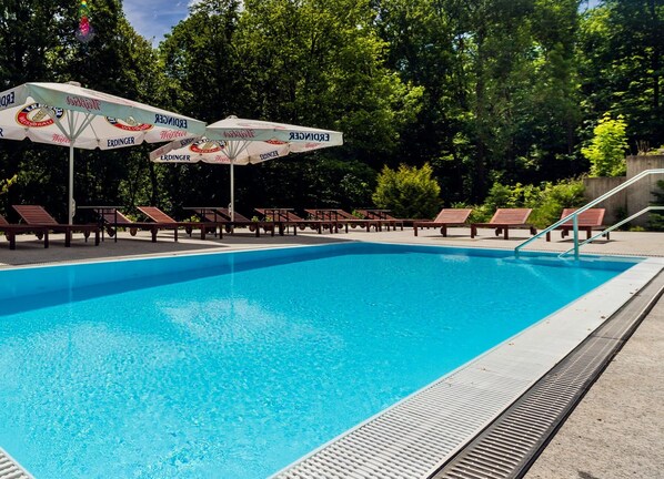 Una piscina al aire libre, sombrillas, tumbonas