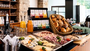 A buffet setup with various food items, including meats, cheeses, and breads, along with a selection of juices and beverages. - Parkhotel Steiger Hohnstein (Hohnstein)