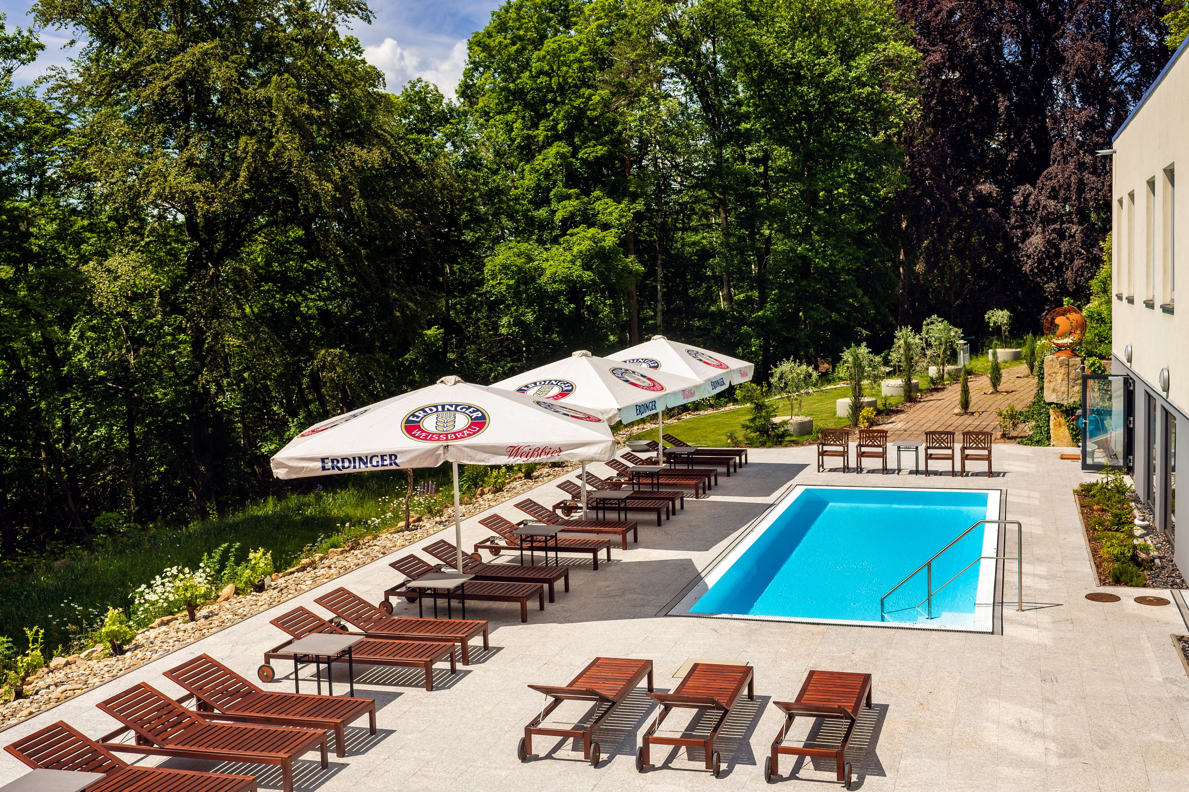 Een buitenzwembad, parasols bij het zwembad en ligstoelen