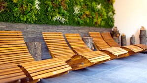 Wooden lounge chairs aligned against a wall with a vertical garden. - Parkhotel Steiger Hohnstein (Hohnstein)