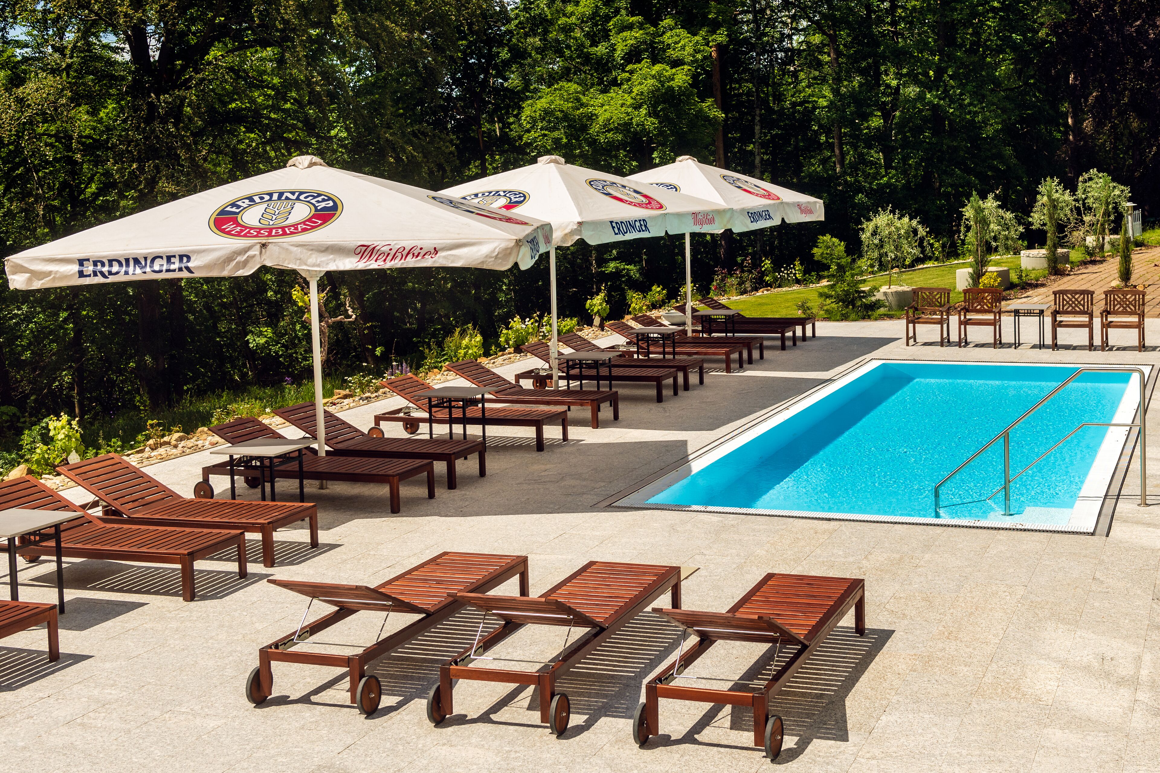 Zona junto a la piscina con tumbonas, sombrillas y una piscina.