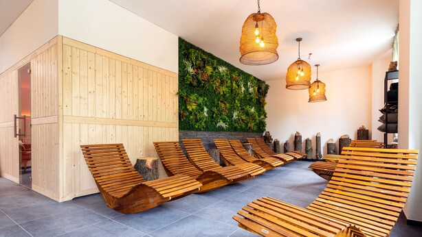 A modern spa area with wooden loungers, a vertical garden wall, and a wooden sauna. - Parkhotel Steiger Hohnstein (Hohnstein)