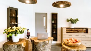 A modern reception area with a wooden desk, a laptop, and a fruit bowl. - Parkhotel Steiger Hohnstein (Hohnstein)