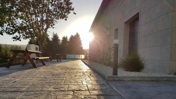 Un espacio al aire libre con pavimento, una mesa de picnic y un edificio con una persiana cerrada.
