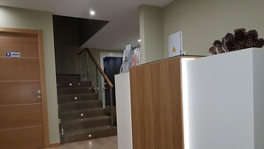 Un pasillo con una puerta de madera que dice 'Lavandería', una escalera y un refrigerador blanco con piñas encima.